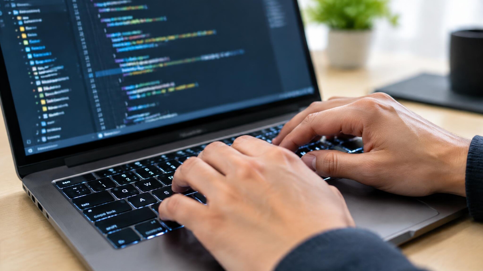 Close-up of hands typing code on a laptop keyboard